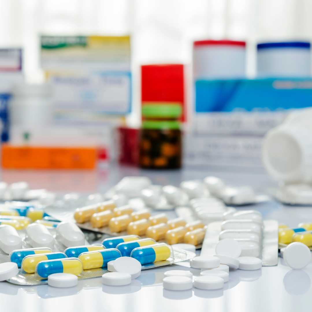 A variety of medicine bottles and pills are scattered across a table